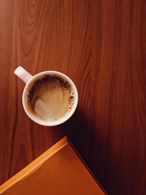 Koffiekopje op houten bureau, plat lag achtergrond en zakelijke mockup, bovenaanzicht