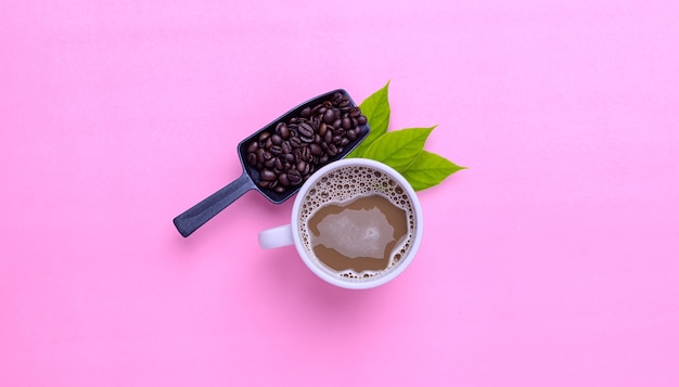 Koffiemok en koffiebonen op een roze achtergrond