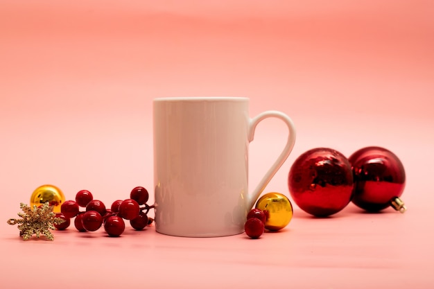 Koffiemok met kerstversieringen eromheen op roze achtergrond