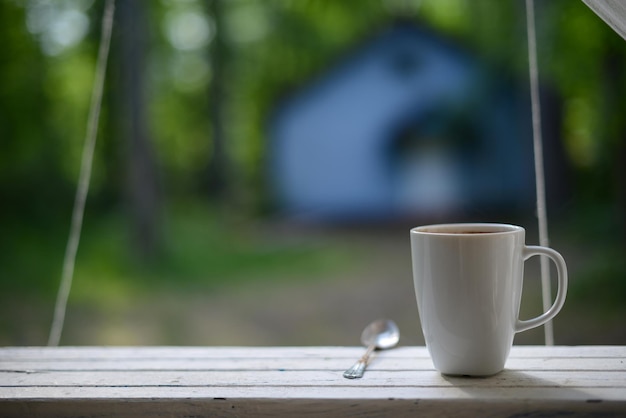 Koffiemok op het spoor op het terras in de tuin wazig huis op de achtergrond kopie ruimte