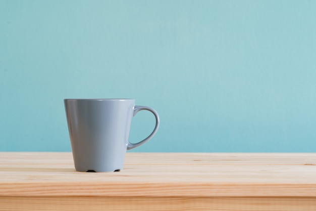 Koffiemokken plaatsen op bruin houten bureau en blauw behang