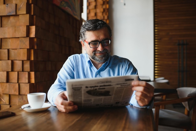 Koffiepauze man koffie drinken en krant lezen in café-bar