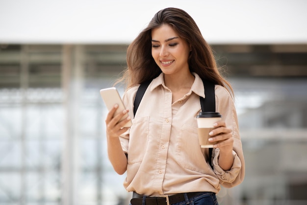 Koffiepauzegadget voor studie blije jonge aziatische studente met een kopje afhaalmaaltijden chatten