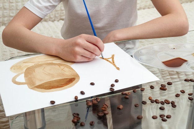 Koffietekeningen Meisje tekent een koffiekopje met koffie in plaats van verf