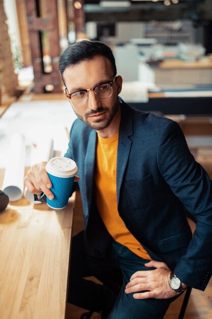 Koffietijd. Bovenaanzicht van een man met een stijlvolle jas die koffie drinkt voordat hij een ontmoeting heeft