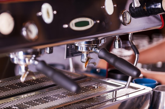 Koffiezetapparaat. Close-upbeeld van metalen espressomachine met iemand die op de achtergrond werkt