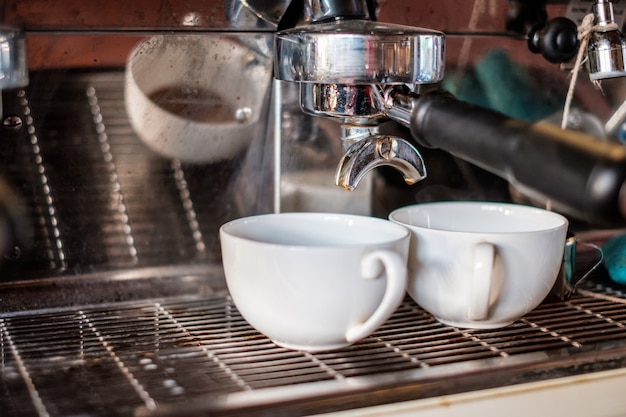 Koffiezetapparaat Espresso-koffie maken in witte kop op teller