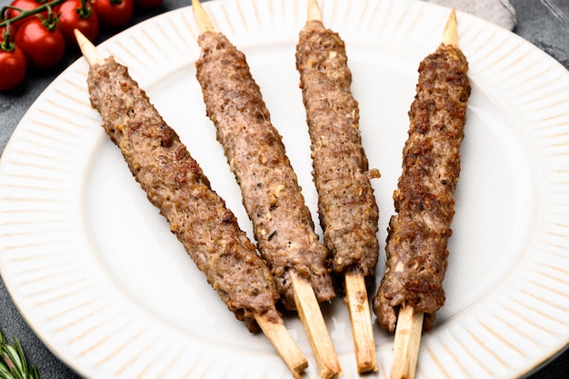 Kofta or lula beef and lamb meat kebabs skewers on plate on gray stone table background