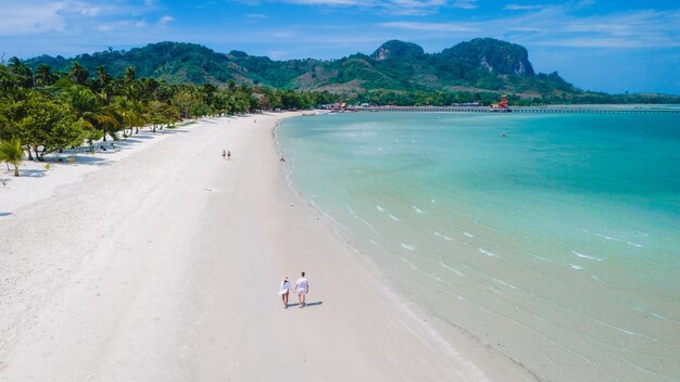 코 무크 (Koh Mook) 의 백색 모래 열대 해변을 고 있는 부부