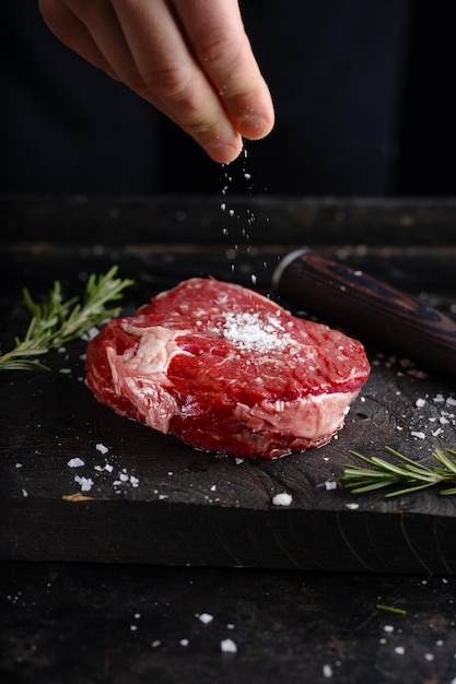 Kok die vers vlees aan boord kookt Donkere achtergrond Koken concept