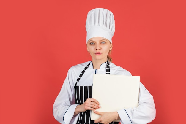 Kok in haar keuken. open receptenboek voor gezond koken. houdt een geheim over ingrediënten. vrouw gebruik kookboek. professionele chef-kok leest recept voor koken. vrouwelijke chef-kok die schotel voorbereidt. ruimte kopiëren.