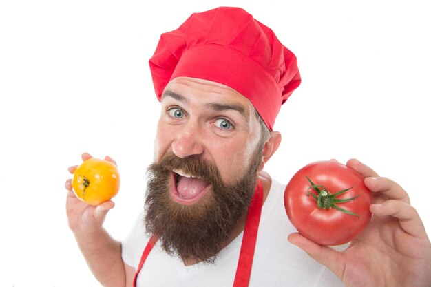 Kok in uniform houdt groenten vast. Rijpe tomaat voor heerlijke maaltijd. Eet verse tomaat. Kies er een. Tomatensaus recept. Gezond kookconcept. Man met baard op witte achtergrond. Chef-kok houdt tomaten.