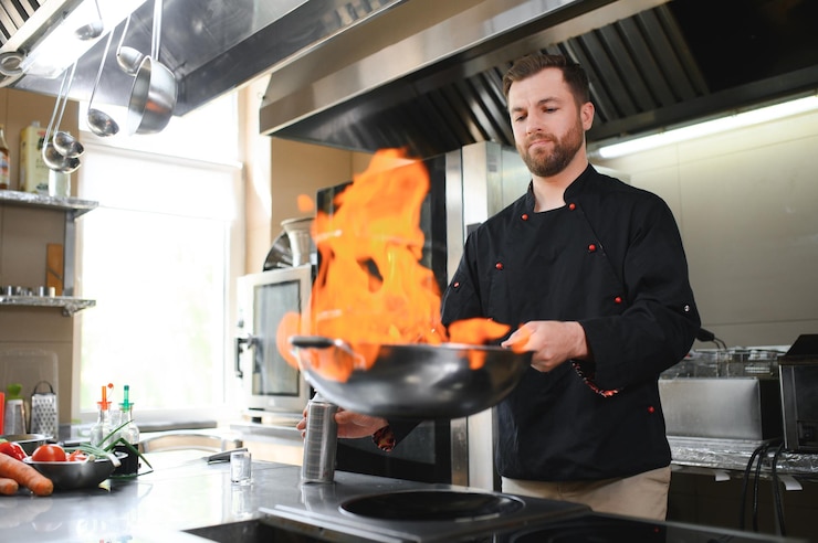 Foto kok koken en flambe doen op eten in de keuken van een restaurant