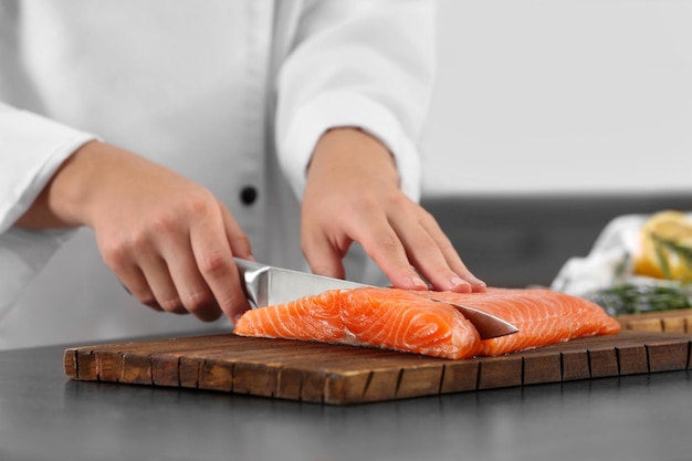 Kok snijdt vers zalmfilet in de keuken