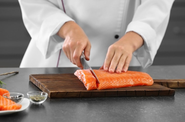 Kok snijdt vers zalmfilet in de keuken