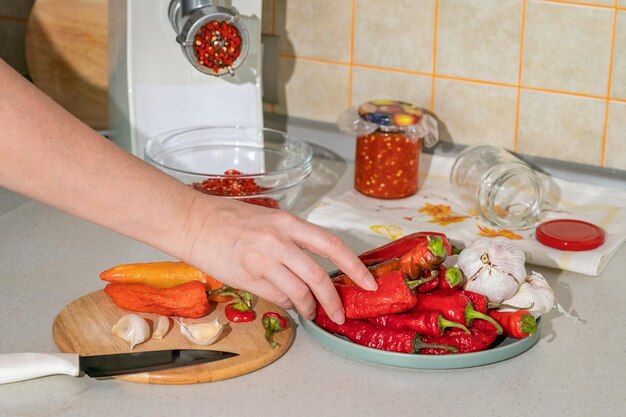 Koken adjika van hete peper en knoflook gemalen in een vleesmolen voorbereidingen voor de winter folk remedie voor griep en verkoudheid