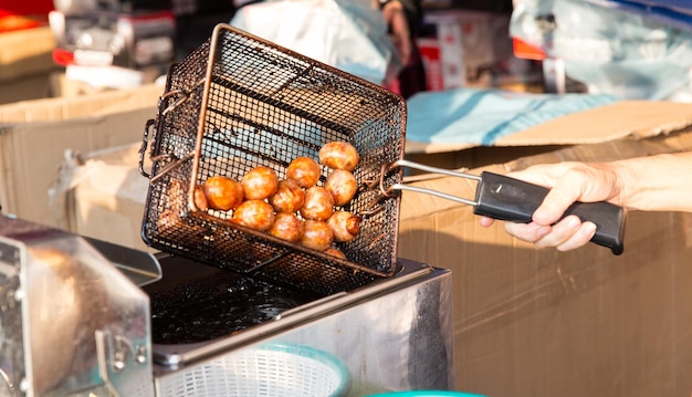 koken, aziatische keuken en voedselconcept - close-up van kokende gehaktballen in olie op straatmarkt