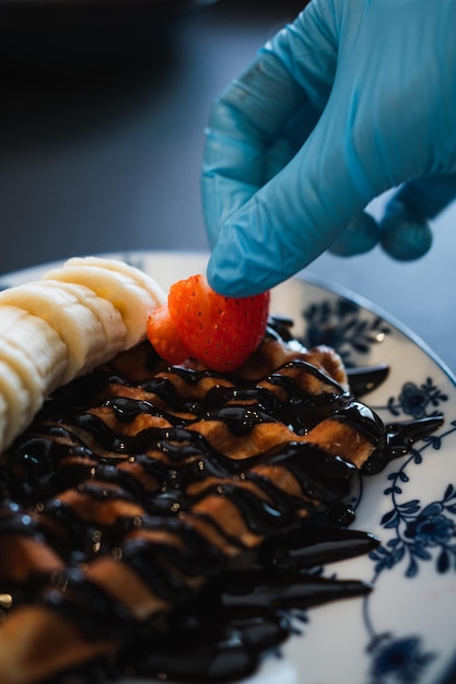 Koken bereidt een chocoladewafel voor met banaan, aardbei en ander fruit Brunchconcept