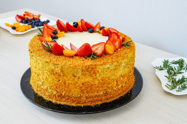 Koken en versieren van een verjaardagstaart met fruit en bessen. aardbeien, bosbessen en physalis. vitamine cake.