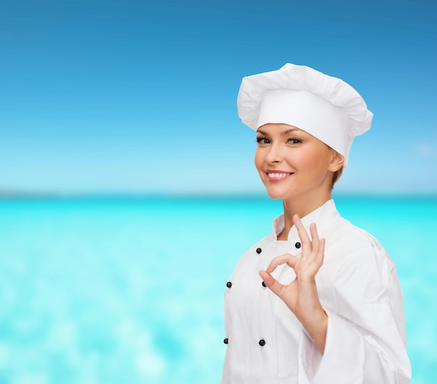 koken, gebaar en voedselconcept - glimlachende vrouwelijke chef-kok die ok handteken toont