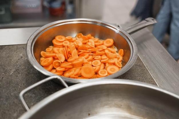 Koken in de eetkamer Gesneden stukjes wortel liggen in de pan