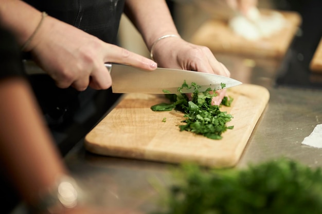 koken in de hand van een restaurantchef-kok die groenten snijdt op een houten plank