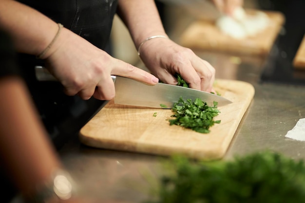 koken in de hand van een restaurantchef-kok die groenten snijdt op een houten plank