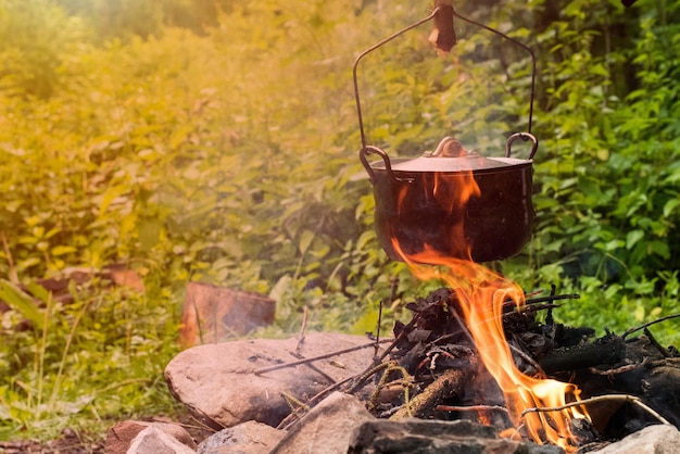 Koken in de roetketel op het open vuur in het bos