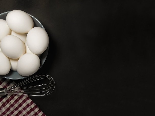 Koken ingrediënten eieren en keukentextiel op een zwarte achtergrond. Kopieer de ruimte.