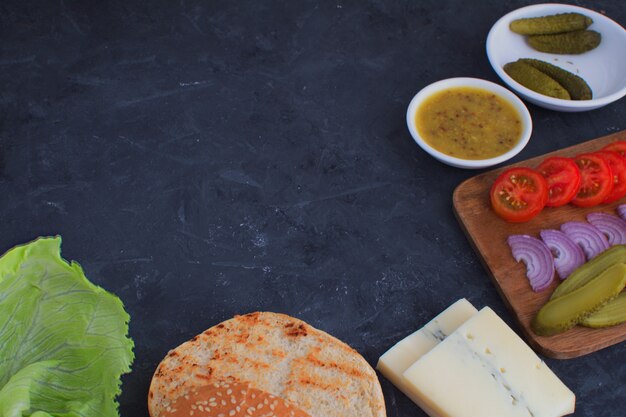 Koken Ingrediënten voor het koken hamburgers Hamburger voorbereiding Houten snijplank Zwarte achtergrond