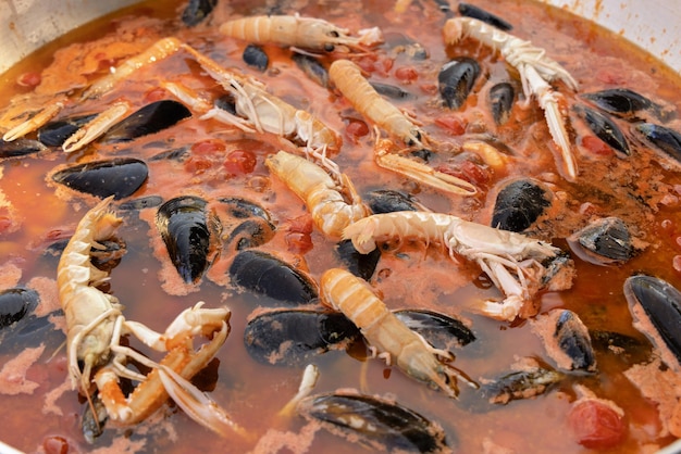 Koken Italiaanse spaghetti allo scoglio pasta met zeevruchten en tomaten close-up in een koekenpan