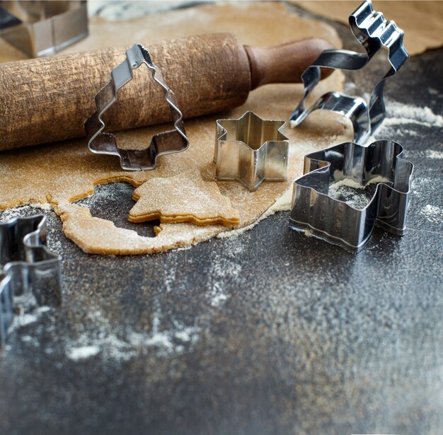 Koken kerstkoekjes met cookie cutters op een donkere tafel