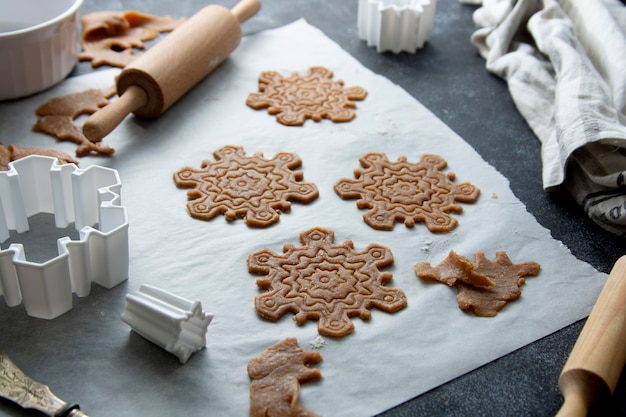 Koken kerstkoekjes sneeuwvlokken vorm. Rauw deeg, koekjesmessen, deegroller.