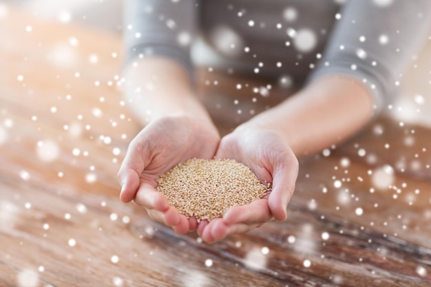 koken, mensen en thuisconcept - close-up van vrouwelijke tot een kom gevormde handen met quinoa