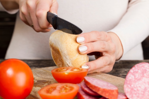 Koken niet bekwame meisjessandwich met broodje, worst en groenten, close-up thuis