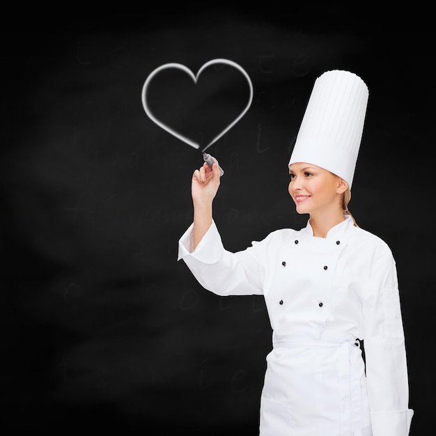 koken, nieuwe technologie, reclame en voedselconcept - glimlachende vrouwelijke chef-kok met markering die iets op virtueel scherm schrijft