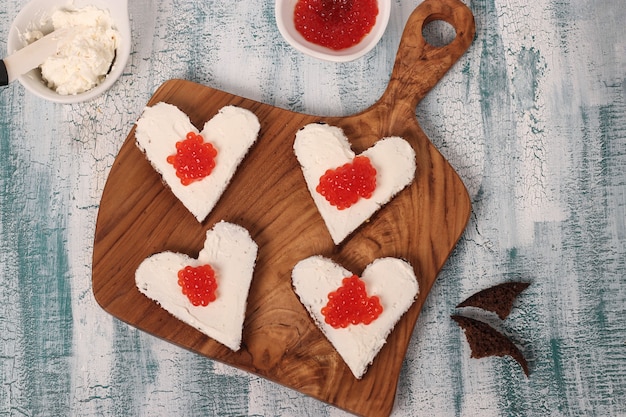 Koken sandwiches met rode kaviaar en roomkaas in de vorm van een hart voor Valentijnsdag, bovenaanzicht