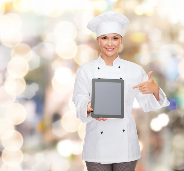 koken, vakantie, technologie en voedselconcept - glimlachende vrouwelijke chef-kok, kok of bakker met tablet pc-computer wijzende vinger naar leeg scherm over lichtenachtergrond