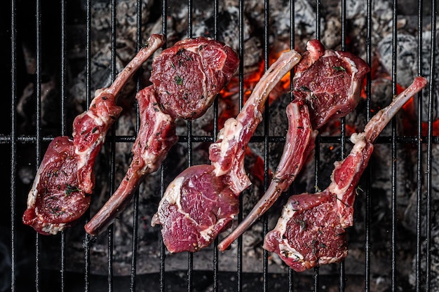 Koken van rauwe lamskoteletten op barbecue, barbecue buiten met vuur. Bovenaanzicht.