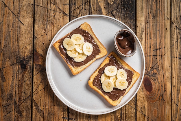 Koken van sandwich met chocolade Hazelnootboter en bananen. Houten achtergrond. Bovenaanzicht.