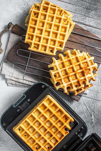 Koken van verse wafels in wafelijzer witte achtergrond bovenaanzicht