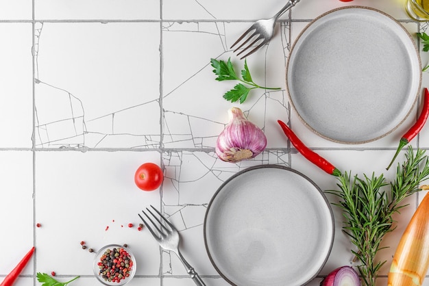 Koken voedsel achtergrond Lege borden met kruiden specerijen kruiden en groenten op witte tegel keukentafel