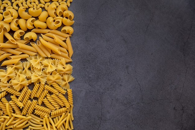 Koken voedsel concept Verschillende soorten pasta op een donkere ondergrond Bekijk van bovenaf