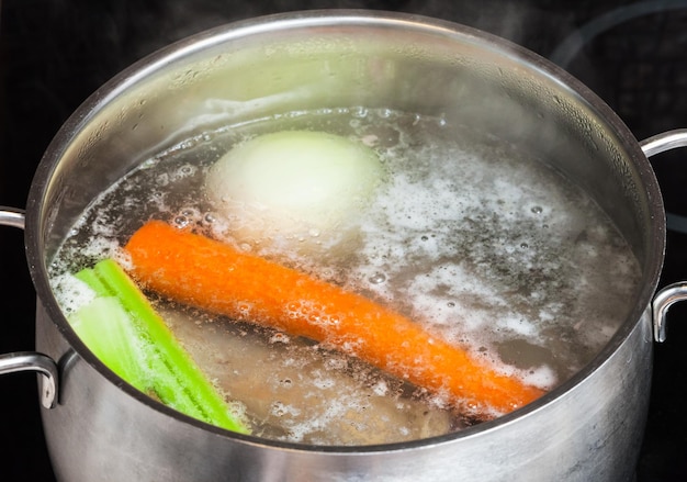 Kokende vleesbouillon in stoofpan close-up