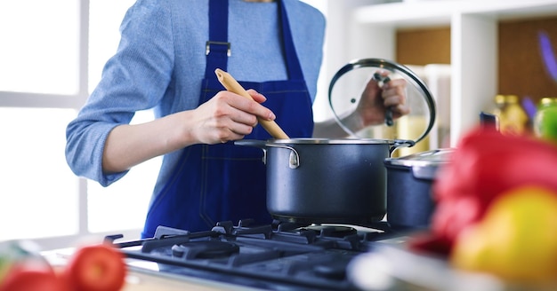 Kokende vrouw in keuken met houten lepel