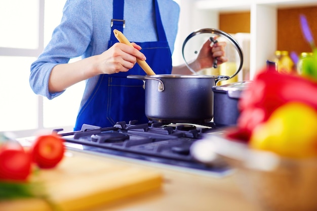 Kokende vrouw in keuken met houten lepel