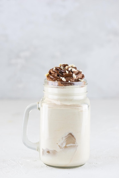 Kokosmilkshake met chocolade en noten op een lichte achtergrond