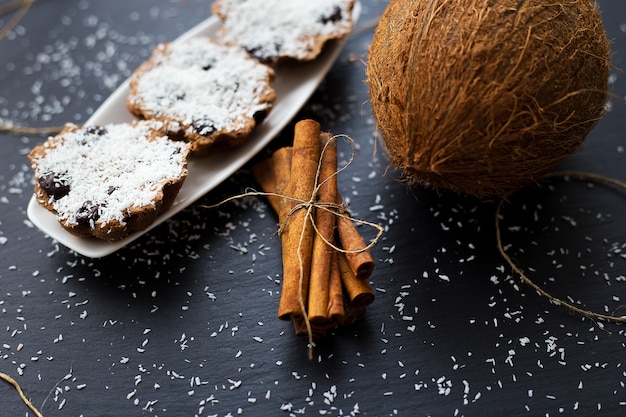 Kokosmuffins met chocolade en kaneel op een zwarte achtergrond en hele kokosnoot