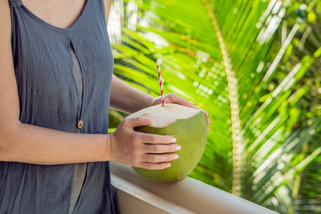 Kokosnoot in mooie vrouwelijke handen op een groene achtergrond. De voordelen van Coconut Water Concept