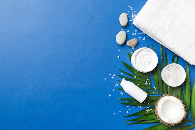 Kokosnoot met potten kokosolie en cosmetische crème op gekleurde achtergrond Bovenaanzicht Vrije ruimte voor uw tekst Natural spa kokoscosmetica en biologisch behandelingsconcept Coconut Spa samenstelling